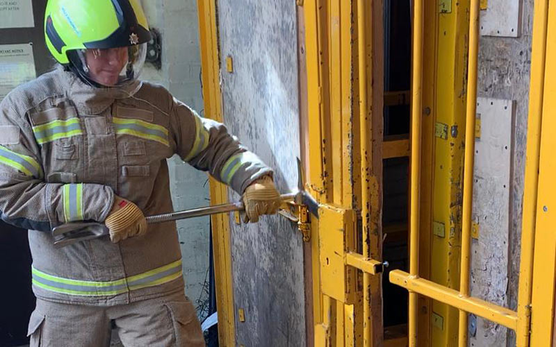 Trainee using a crowbar to open a metal door.